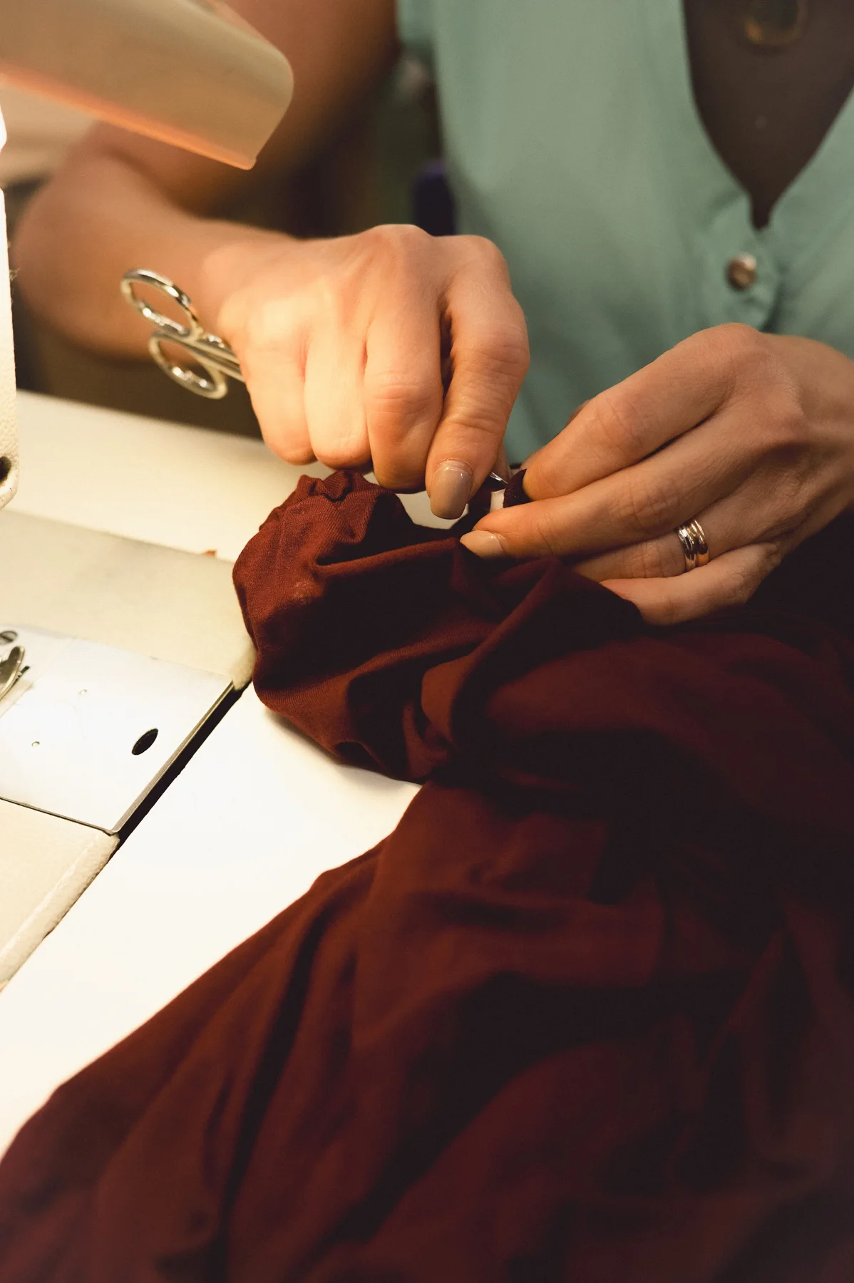 Hands carefully working on the detail of a burgundy garment