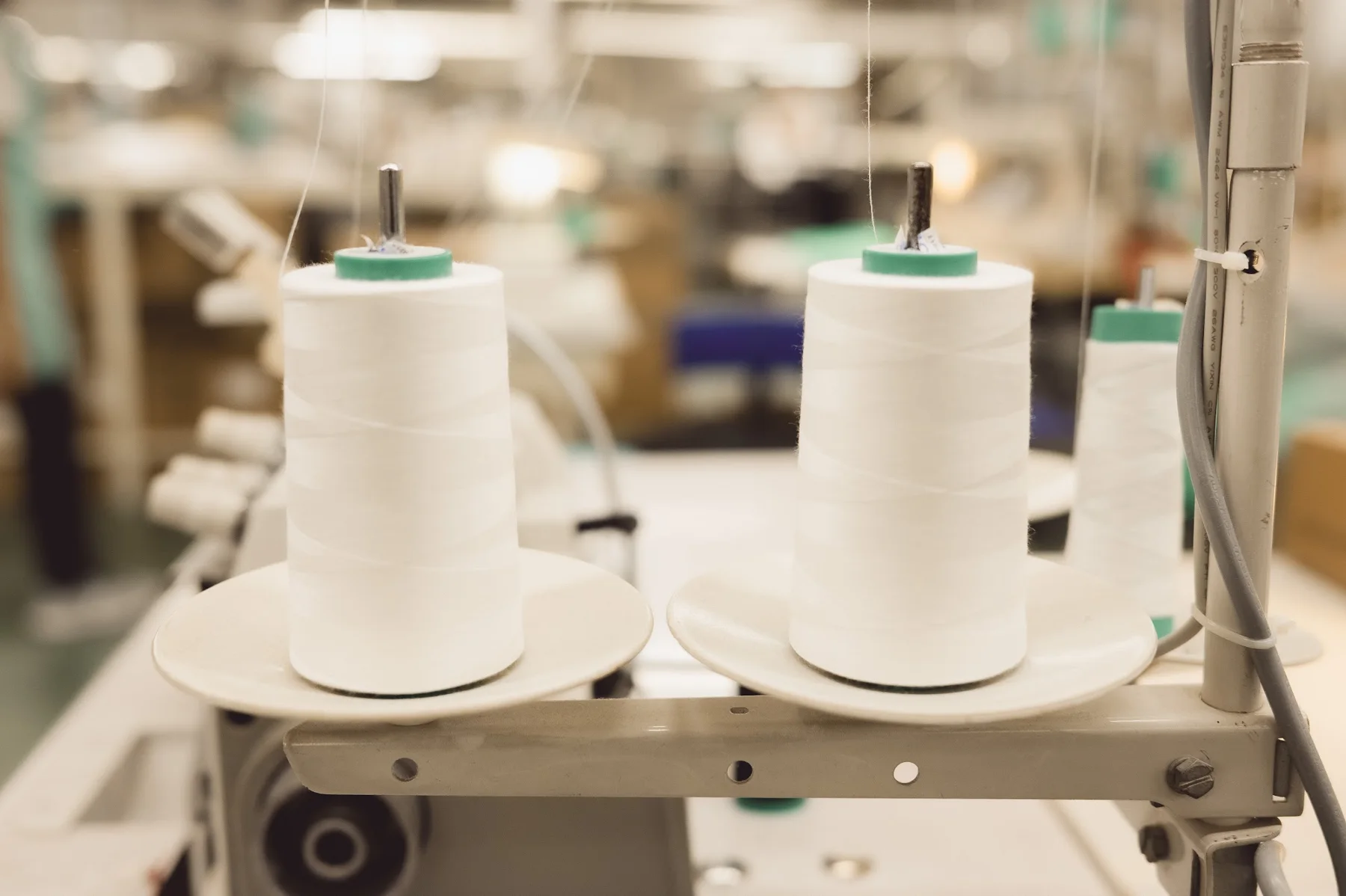 Cream thread spools on industrial sewing equipment
